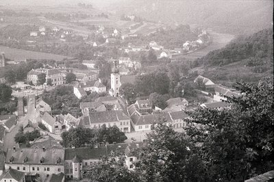 High-angle view of a European town, likely Central or Eastern Europe, featuring tightly-packed buildings with gabled roofs cl...