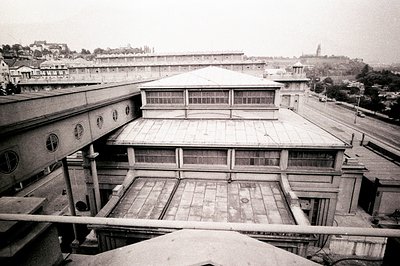 A view of a large, modernist institutional building, possibly a hospital or school. Geometric architecture with flat roofs an...
