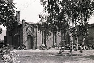 Detailed image of a brick building with elaborate gabled entrance and window detailing. Appears to be a factory or workshop, ...