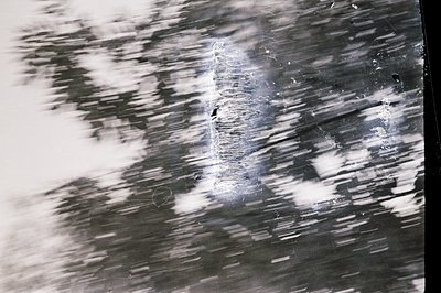Striated, blurred image reveals a central focal point resembling a distorted window or opening within a dark, textured backgr...