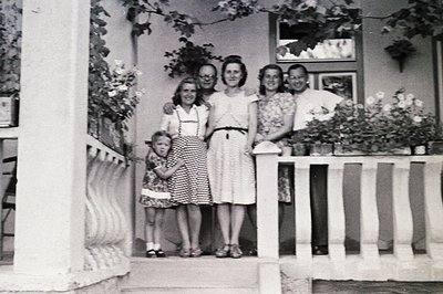 A family portrait, circa 1950s, showcases a young girl hugging an older man, flanked by two women in vintage summer dresses. ...