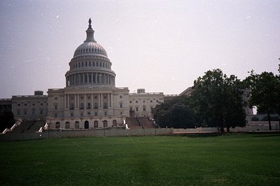 The U.S. Capitol Building dominates the view, showcasing its neoclassical architecture and iconic dome. Lush green lawn exten...