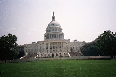 The United States Capitol Building dominates the frame, viewed across a grassy lawn. Classical architecture features a promin...