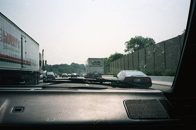 First-person view from a car dashboard showing a congested highway. A semi-truck with "Magyar 450-Move" branding dominates th...