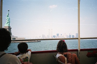 View from a ferry, capturing the Statue of Liberty and the New York City skyline, including the World Trade Center towers. Tw...