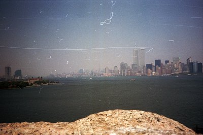 Vantage point above water shows the New York City skyline, including the World Trade Center towers, hazy due to atmospheric c...