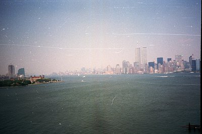 Vast body of water, likely the New York Harbor, features a distant New York City skyline dominated by the iconic Twin Towers....