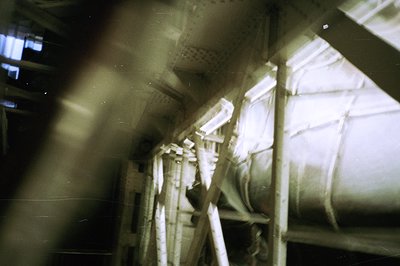 A stark, grainy interior view shows scaffolding and machinery, likely industrial or construction-related. The scene's high co...