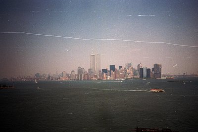 Panoramic view of the New York City skyline, featuring the prominent twin towers. A ferry boat traverses the water in the for...
