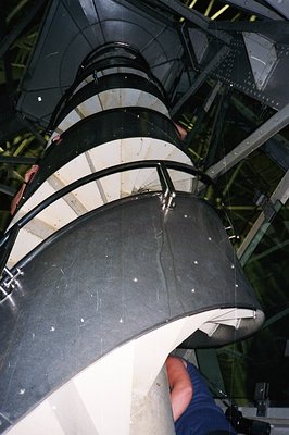 A low-angle view within a large, circular structure, likely an observation deck or tower. The metal architecture features cur...