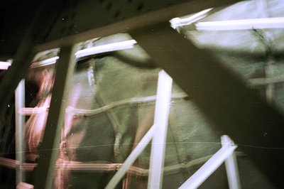 Motion blur captures a figure amidst institutional architecture - possibly a hallway or corridor. Fluorescent lighting casts ...