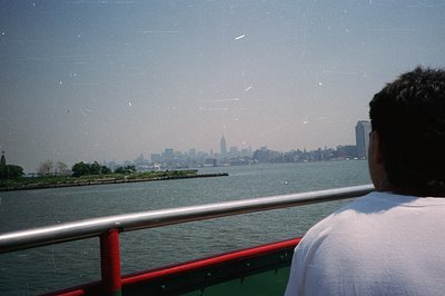 View of the Manhattan skyline across a body of water, likely New York Harbor. The scene is captured from a vantage point on a...