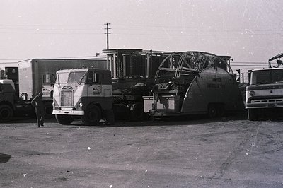 Vintage flatbed truck transporting a large, cylindrical industrial tank or silo, likely for grain or chemicals. Mid-20th cent...
