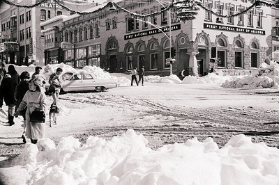 Classic 1960s downtown street scene blanketed in heavy snow. Prominent First National Bank of Arizona building with ornate si...