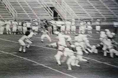 Blurred motion shot of a large group of schoolchildren sprinting on a track, likely during a PE class or sports event. Empty ...