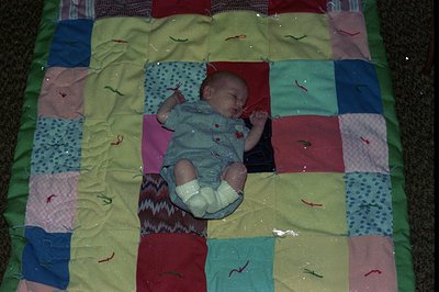 Vintage patchwork quilt with geometric blocks in red, blue, green, and floral patterns, featuring red embroidered stitching. ...