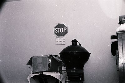Vintage black-and-white industrial scene featuring a classic octagonal STOP sign mounted on a textured wall. Below it, an old...