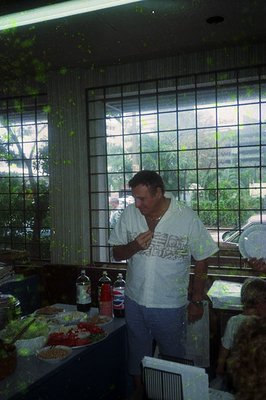 Indoor scene featuring a man in a white T-shirt with a QR code design, standing near a buffet table. The table displays assor...