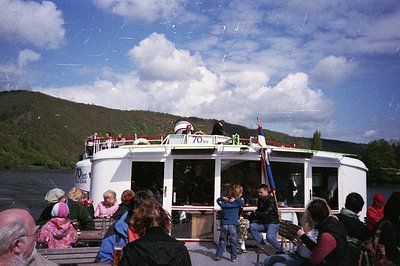 Vintage riverboat ferry labeled "70" transporting passengers across a scenic lake, surrounded by lush green hills under a par...