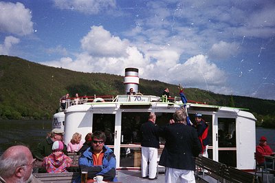 Vintage riverboat cruise with "70th" anniversary marking, likely 1970s. White vessel with red accents, carrying passengers in...