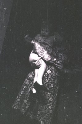 Black-and-white portrait of a person in motion, blurred by rain or camera shake. Patterned dress with intricate floral embroi...