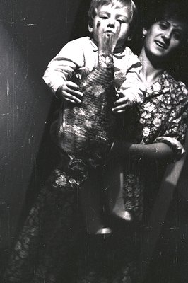 A tender black-and-white moment: an adult holds a child in a patterned sweater, both laughing or crying. The child’s face is ...