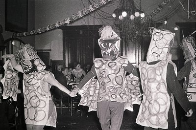 Black-and-white photo of three children in elaborate, textured costumes resembling giant, stylized mushrooms or toadstools, h...