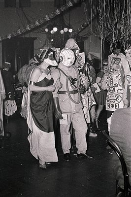 Costumed performers in a theatrical or carnival setting, likely mid-20th century. Left: woman in draped fabric with headpiece...