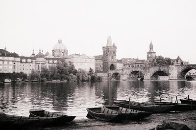 Historic black-and-white view of the **Charles Bridge (Karlův most)** in Prague, featuring its iconic Gothic towers and domed...