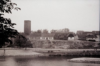 An elevated, panoramic view of a village featuring a prominent tower, likely a church or defensive structure. Buildings displ...
