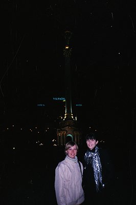Two women stand in front of the Mariyinsky Palace in Kyiv, Ukraine, at night. The palace is illuminated, revealing its neocla...