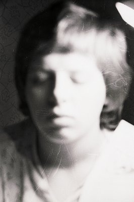 Striking portrait of a young person, likely male, with short, styled hair. The image exhibits a blurred quality and surface s...