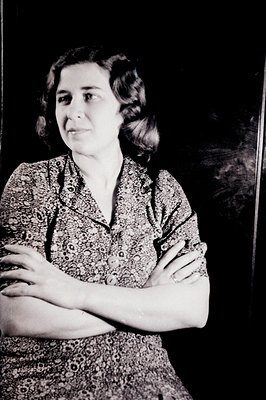 Elegant portrait of a woman in a floral print blouse with sleeves folded across her arms. She has a soft, contemplative expre...
