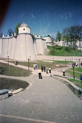 Exterior view of stone fortress walls & gatehouse, likely a coastal defense structure. A sloped, grassy area rises behind the...