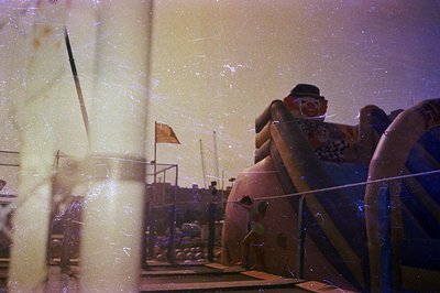 A vintage color photo shows a large inflatable clown slide at an amusement park. Visible details include a flag, crowds of pe...