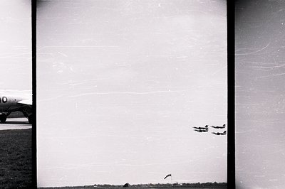 Striking black and white aerial shot depicts a formation of four aircraft performing a synchronized maneuver against a flat h...