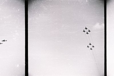 Six aircraft execute a coordinated aerial display, leaving trails of condensation against a bright sky. The composition exhib...