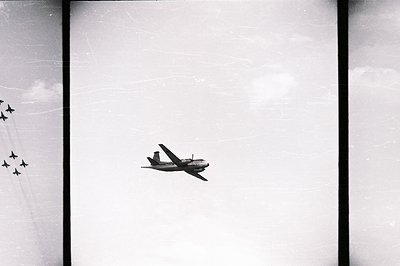 A vintage black and white photograph captures a military formation of aircraft, likely a training exercise or airshow. The le...