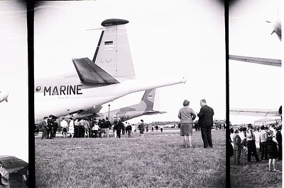 A crowd gathers to view a United States Marine Corps Douglas C-124 Globmaster transport aircraft on a grassy airfield. The ta...
