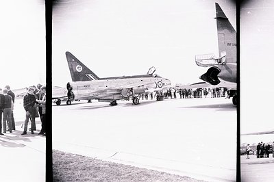 A U.S. Air Force B-52 bomber sits on an airfield apron, viewed by a crowd of onlookers. The aircraft’s distinctive tail marki...