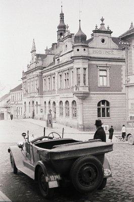 Willys Jeep, likely post-WWII, parked before a grand, multi-story building with ornate detailing and a central dome. Signage ...