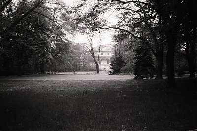 A formal garden leads to a stately manor house framed by mature trees. Likely an estate or historical property, it showcases ...