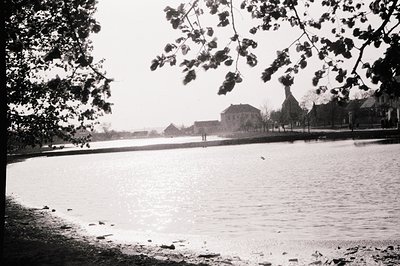 A panoramic view of a seaside landscape, likely Eastern Europe. A calm body of water reflects sunlight, with a distant view o...