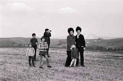 A family portrait in a field, likely Bulgaria, capturing everyday life. Three children in winter clothing, a teenage boy with...