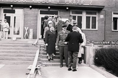 Group exiting a building in Prague, Czechoslovakia. Men in suits and uniforms are accompanied by women in coats and hats. The...