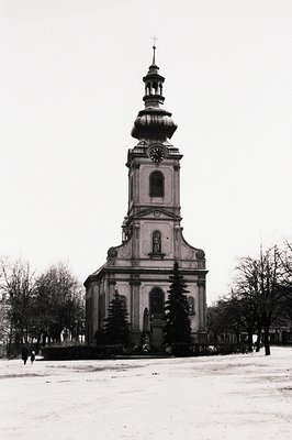 Classic Baroque church facade with a distinctive onion-domed bell tower. Snow-covered grounds & bare trees frame the building...
