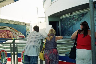 A family of three observes a mural depicting marine life and a stylized ship design. The composition includes a staircase and...