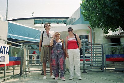 Three individuals stand in front of a sign reading "ATA AQUARIUM," likely in Bulgaria. The man wears a patterned shirt & shor...