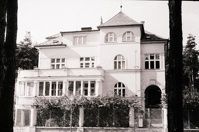 Elegant, three-story villa with a distinctive curved balcony and arched windows. The architecture suggests late 19th/early 20...