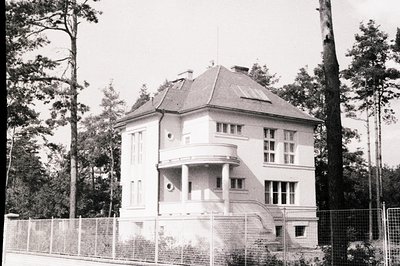 A detached, two-story house with a prominent, steeply pitched roof and a projecting, curved bay window. Features include a sm...